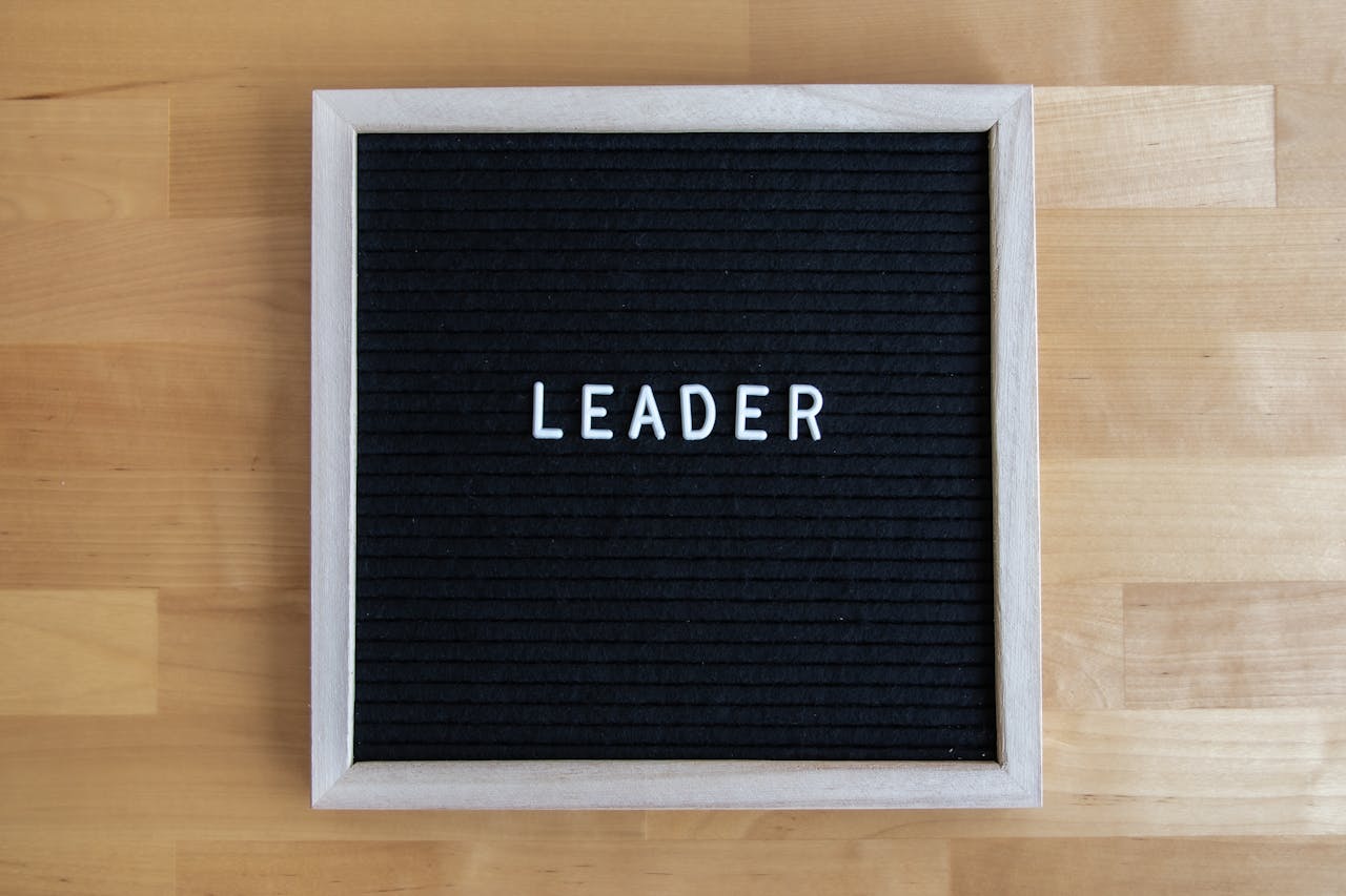 Black letter board displaying the word u0022LEADERu0022 with a wooden frame on a wooden surface.